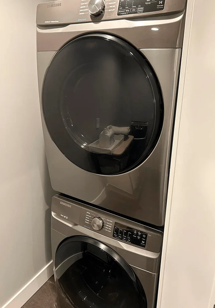 A clean, modern stackable washer and dryer unit in a laundry closet, showcasing a move-in ready home.