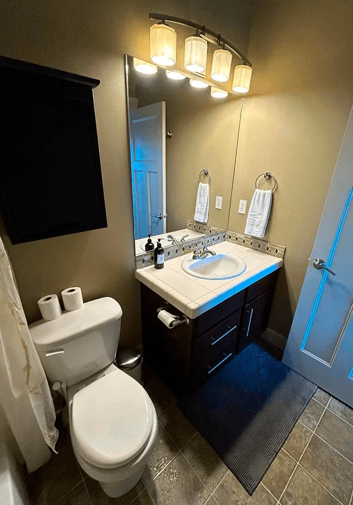 A clean bathroom with a dark wood vanity, tiled countertop, and a sanitized toilet, ready for use after a professional cleaning.
