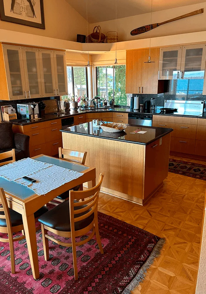 A spacious, clean kitchen with wood cabinets, a central island, and polished parquet floors, ready for family gatherings.