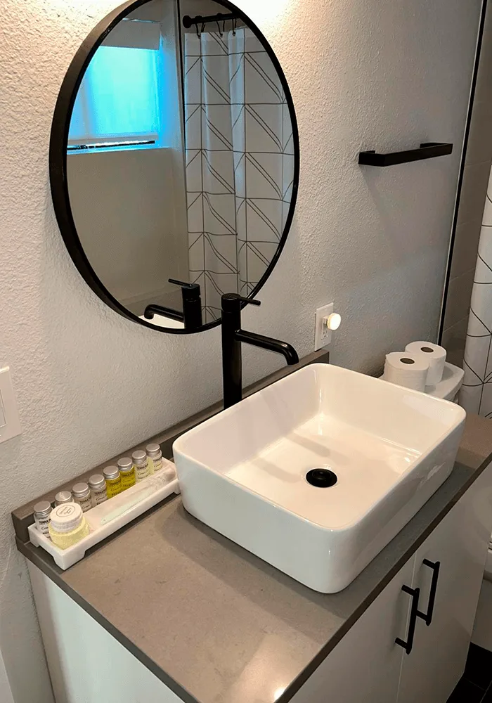 A modern bathroom vanity with a white vessel sink, matte black faucet, and a clean countertop prepared for guests.