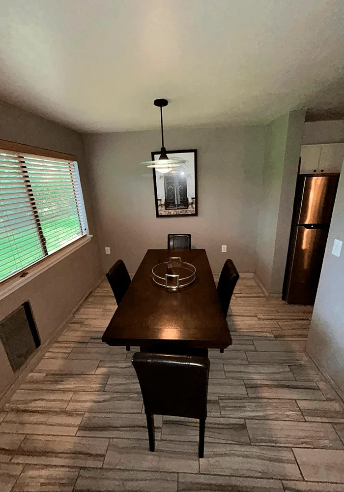 A clean dining room with a dark wood table, modern chairs, and professionally cleaned tile flooring, ready for a meal.