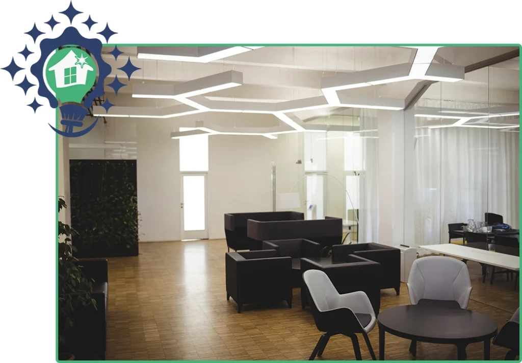 Modern and clean office lounge area with comfortable seating, wooden floors, and contemporary lighting, featuring a cleaning service logo.